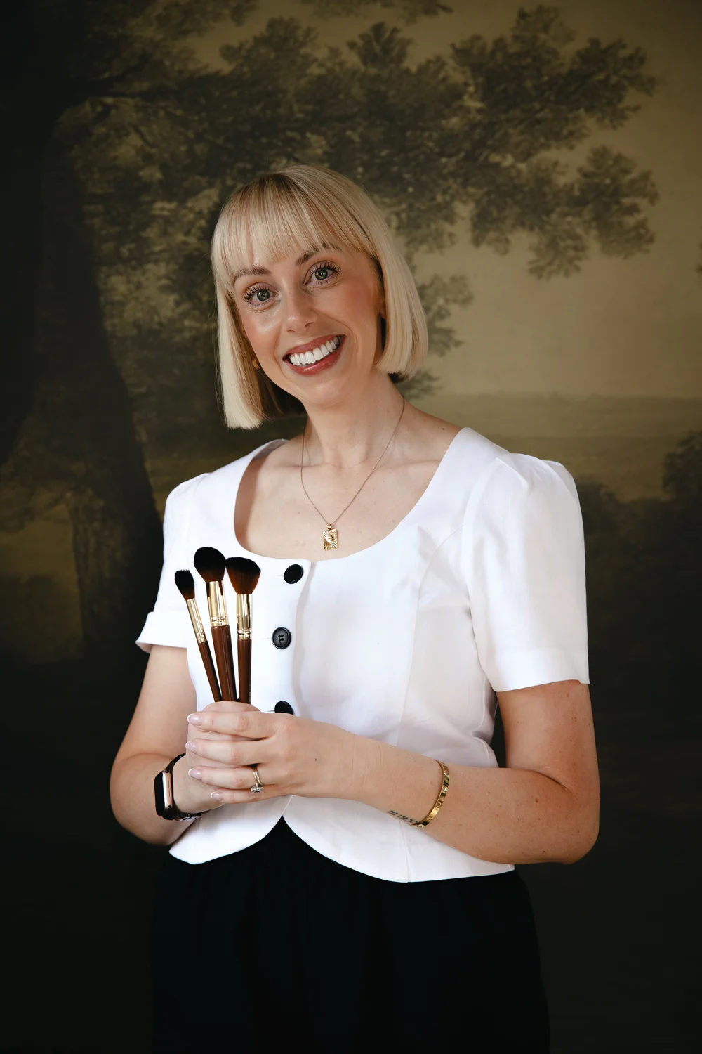 Becci Young smiling and holding her makeup brushes