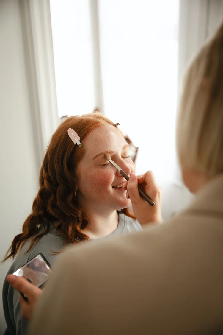 A client smiling while her makeup is applied