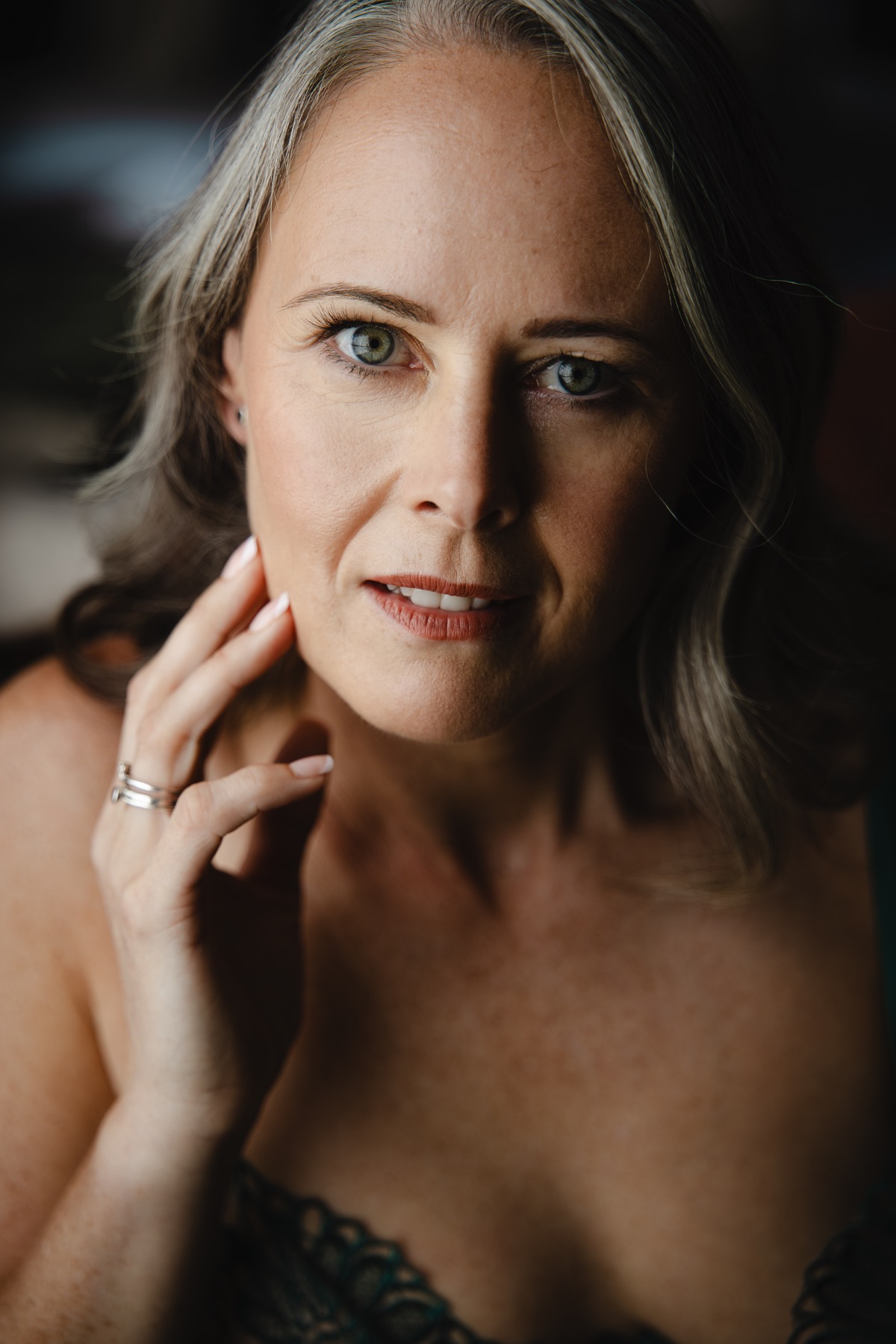 A client smiling gently with her hand beside her face