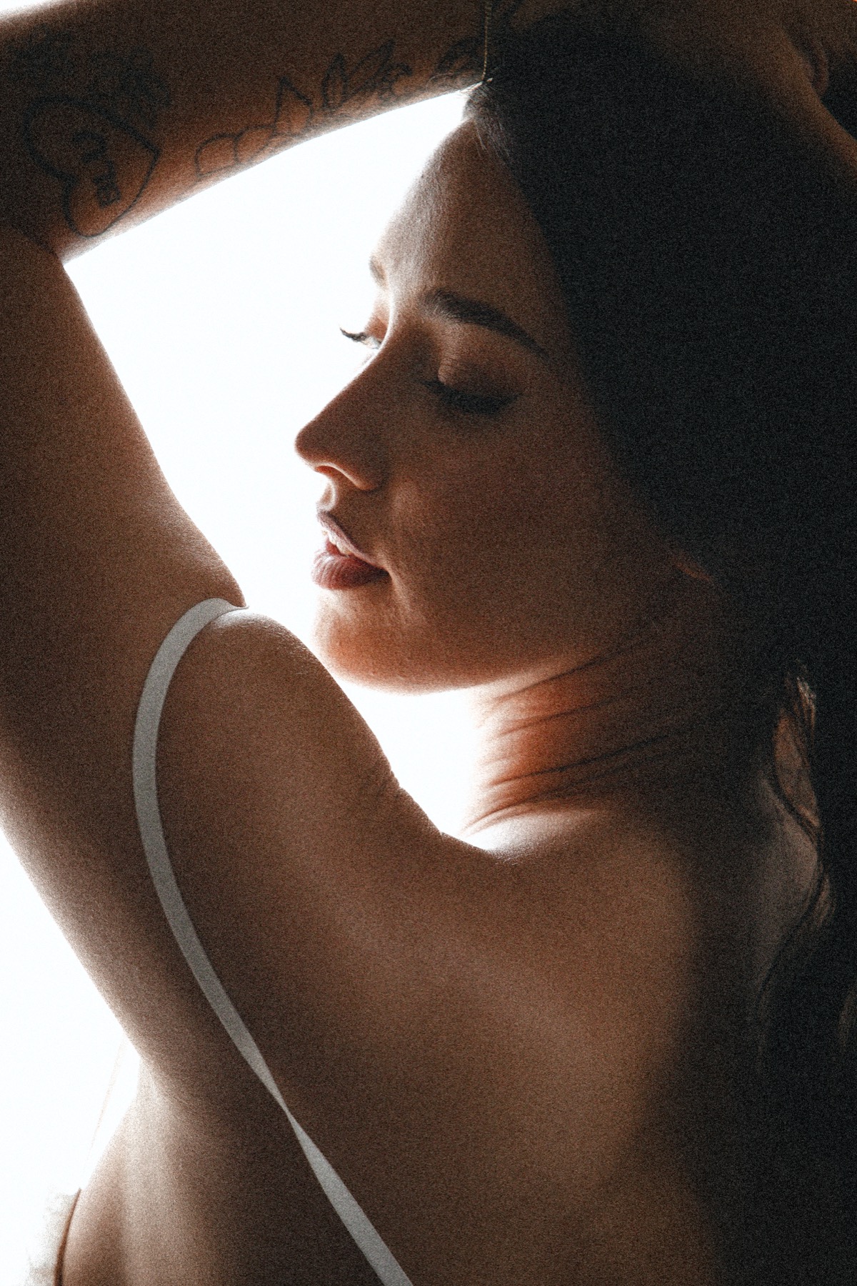 A softly lit profile portrait with an arm framing the face
